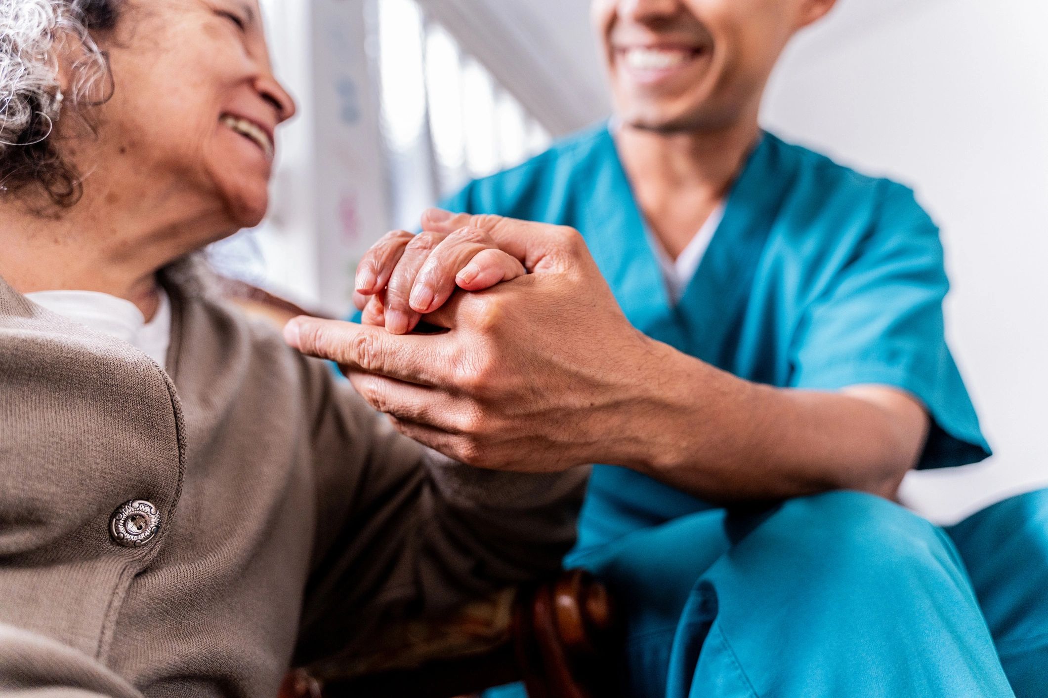 Caregiver holding hands with an older adult at home